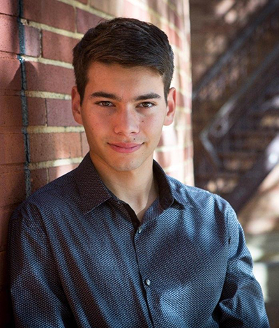 Heand shoulders portrait of young man leaning against brick wall