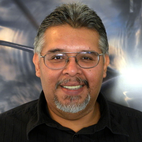 Head and shoulders portrait of Eric against a futuristic/comic space gray background.