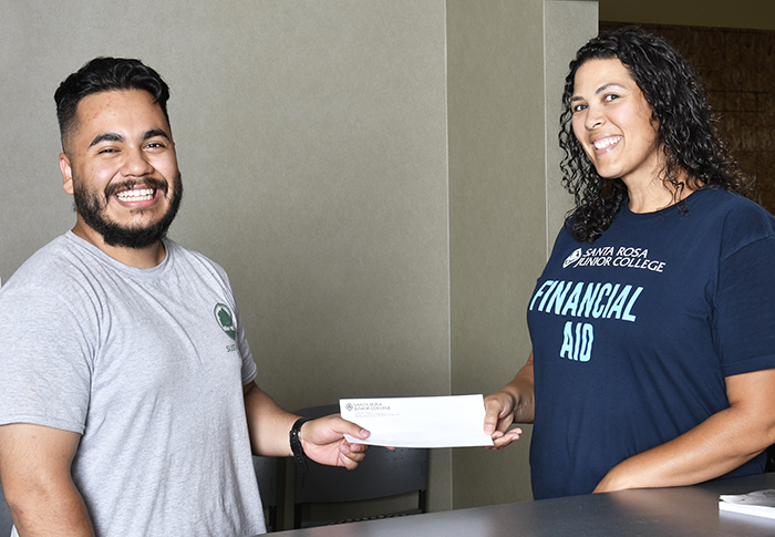 Smiling financial aid staffer handing envelope to smiling student