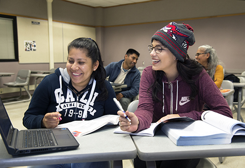 Two smiling students at desks