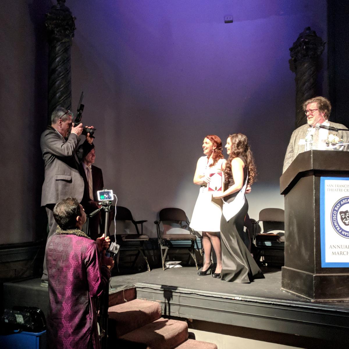 Award winners onstage, being photographed