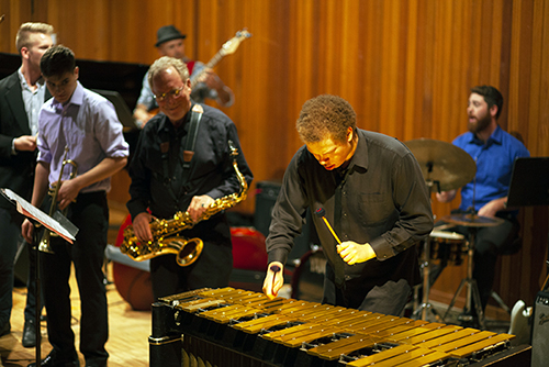 Jazz combo, with marimba player in foreground, with sax, trumpet, and drums visible behind.