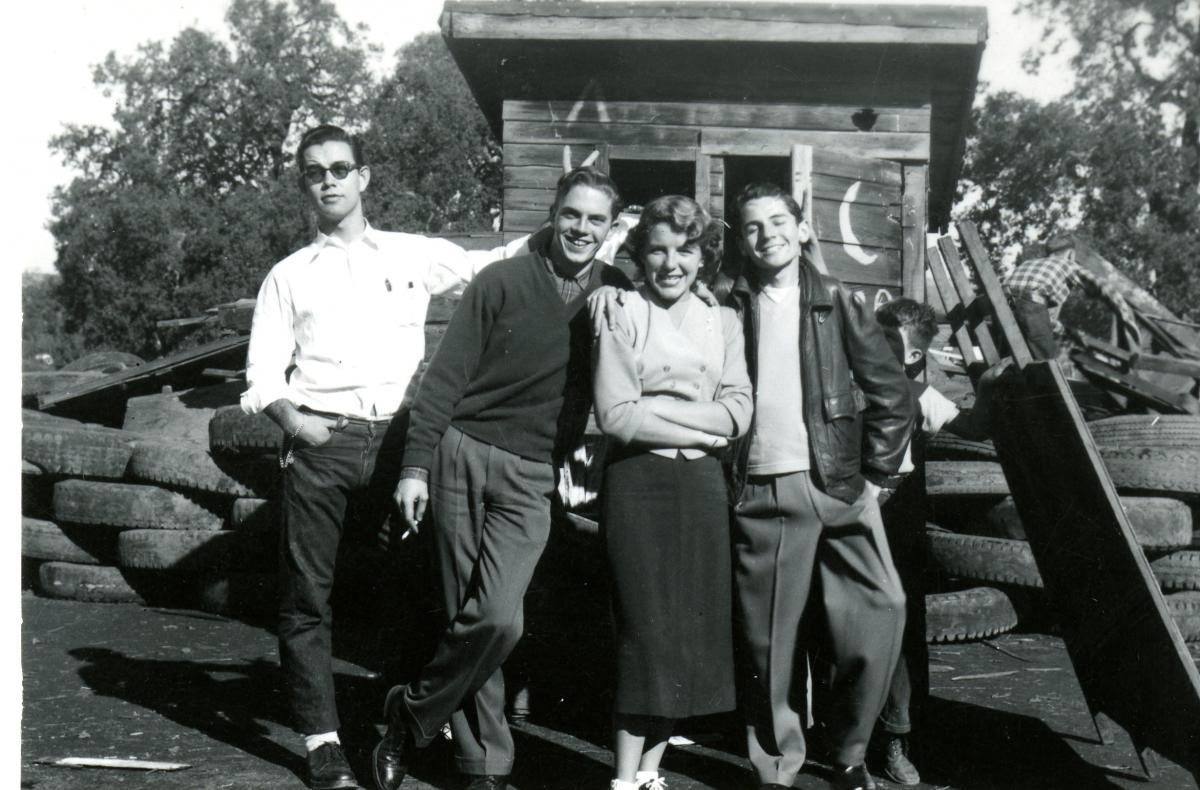 students leaning against old shack