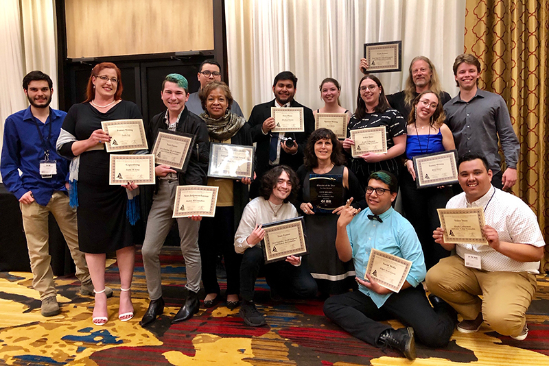 Crowd of smiling students and faculty in a hotel ballroom, holding award certificates.