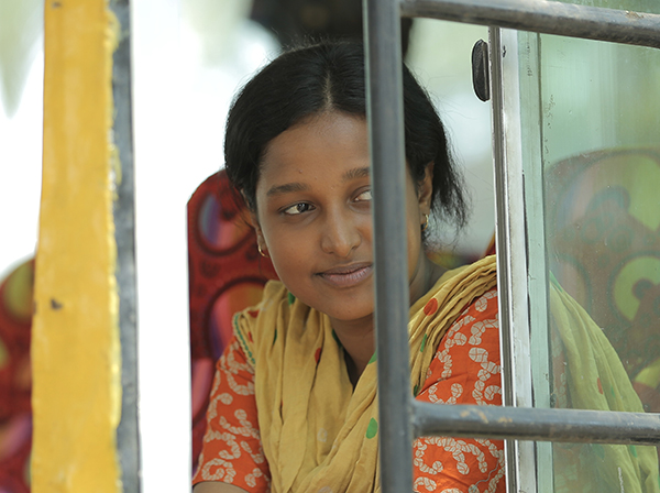 Young Desi woman dressed in red and yellow sari, looking out window
